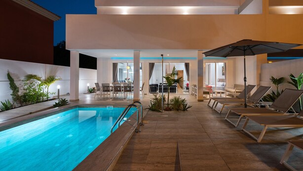 Et moderne poolområde med liggestole og et spiseområde.