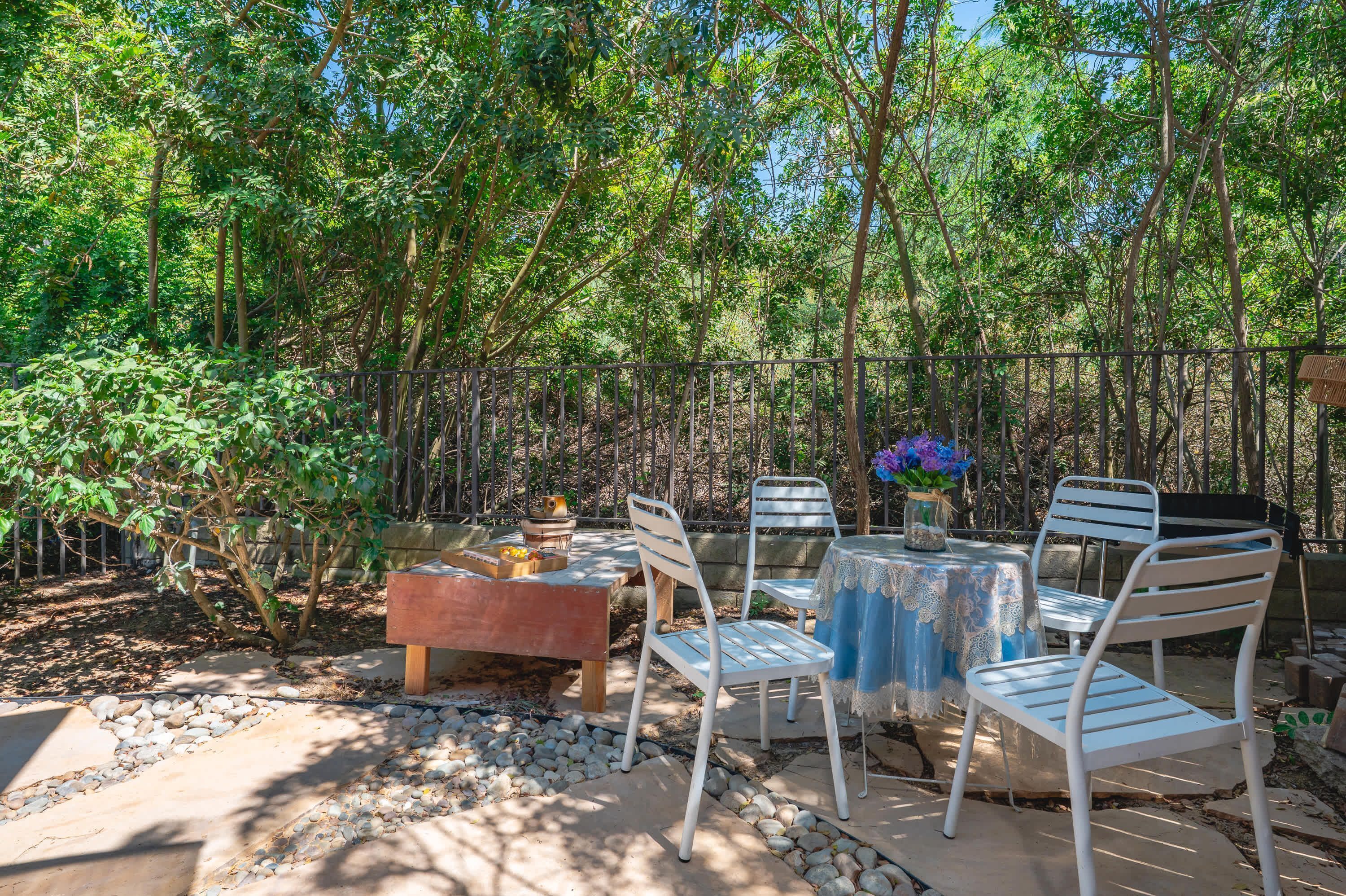 An outdoor patio with a table and chairs, surrounded by a bamboo fence and trees.