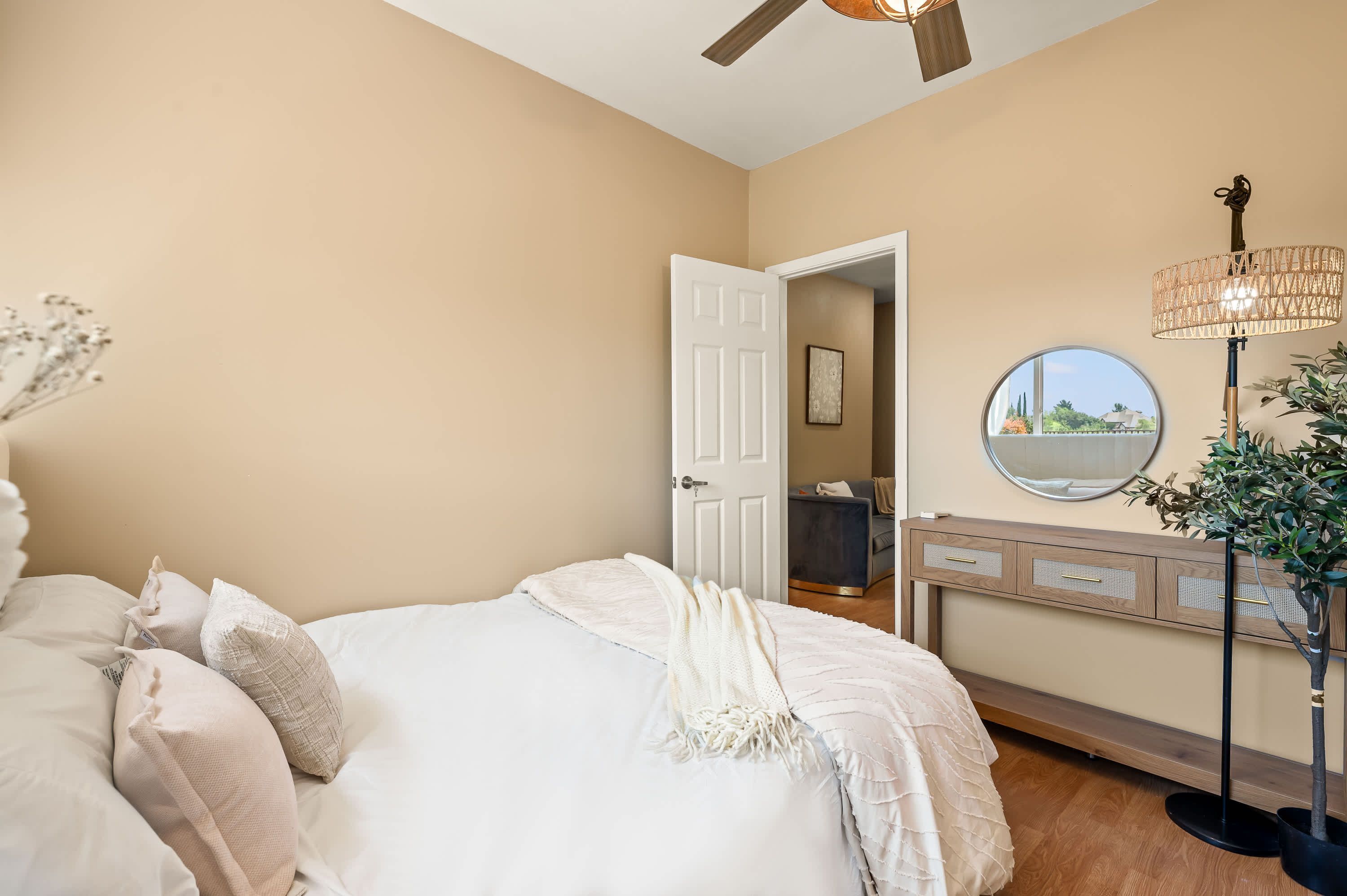 Un dormitorio con cama, mesita de noche, lámpara y vistas al exterior a través de una ventana.
