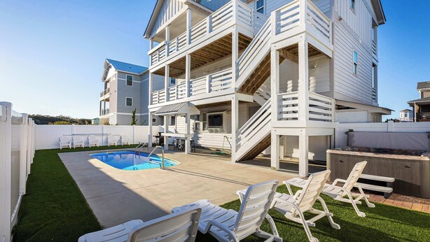Uma casa de dois andares com piscina, área de estar ao ar livre e escada que dá acesso ao andar superior.