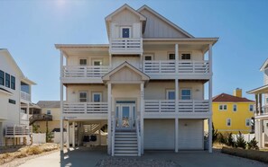 A multi-story beachfront house with a central entrance, balconies, and a garage. - Luxury Corolla Home, 3 Mins to Beach & Lake Views! (Corolla)
