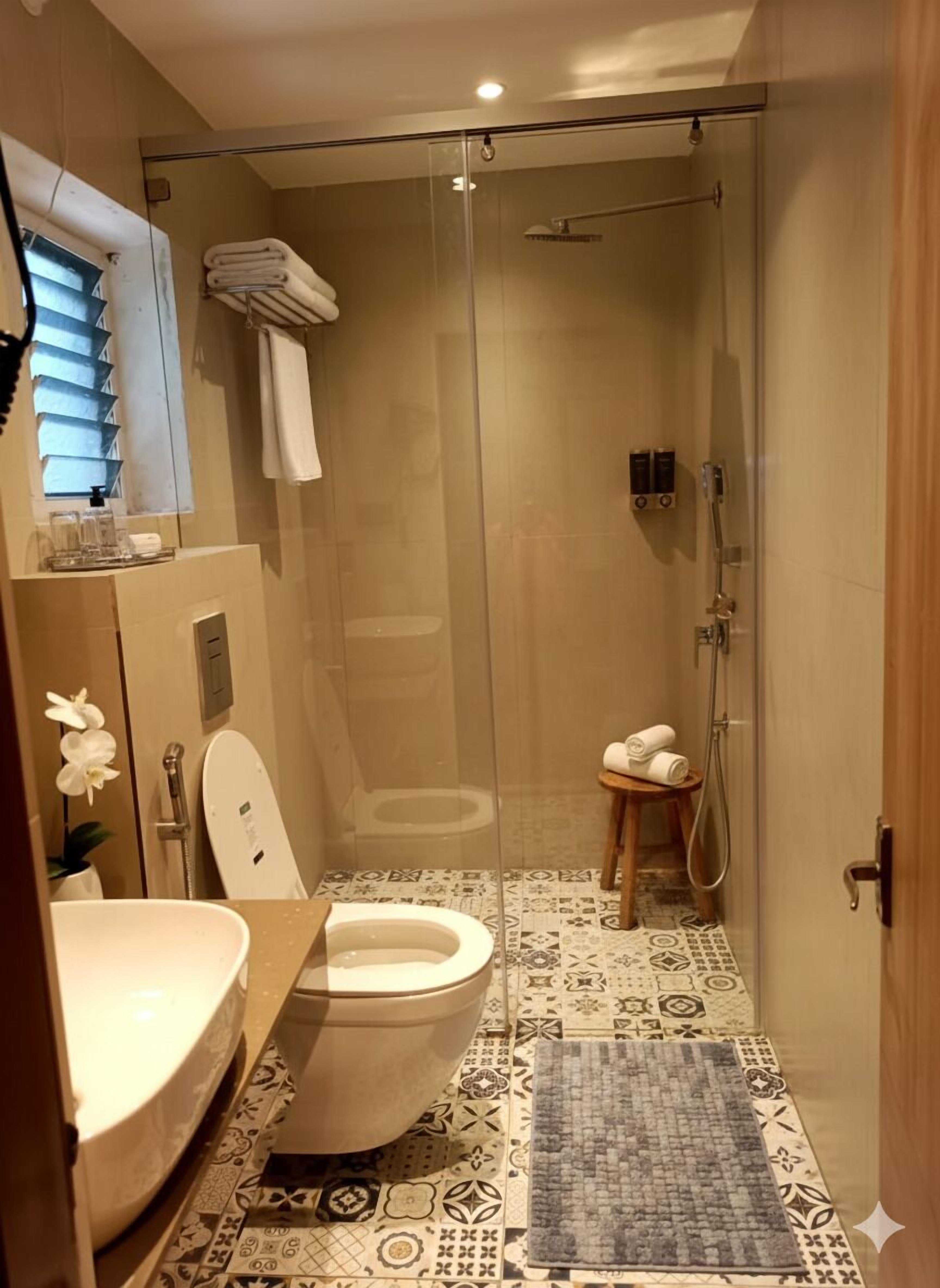 A bathroom with a toilet, sink, and shower area.