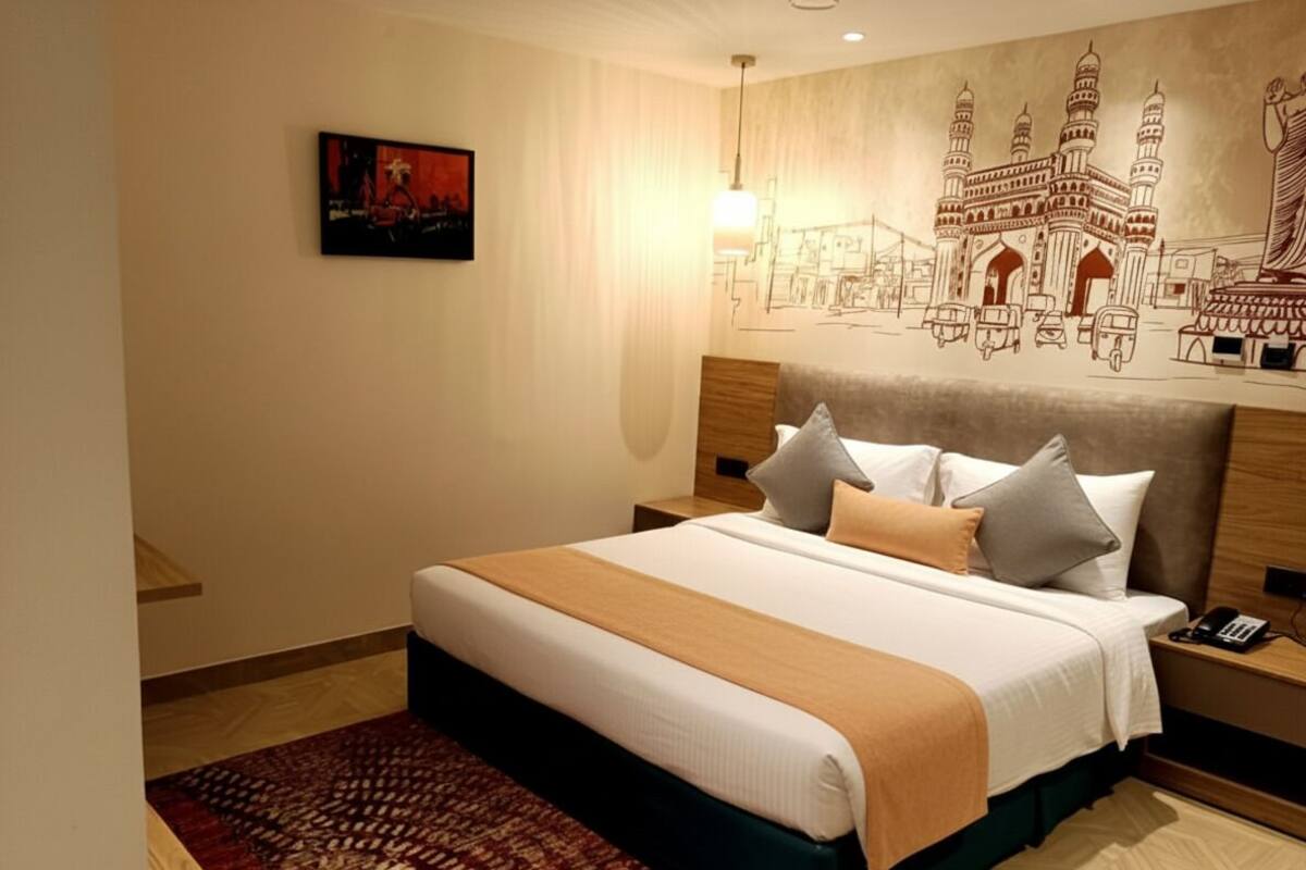 Una habitación de hotel con una cama grande, una mesita de noche, una lámpara y un mural en la pared.
