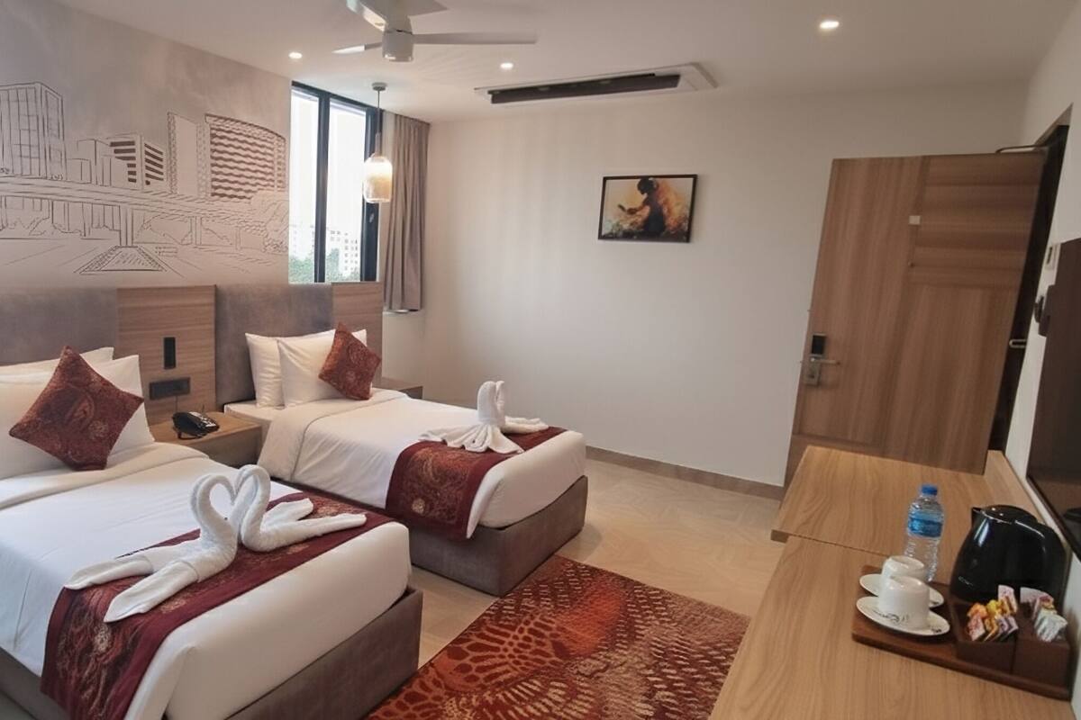 Habitación de hotel con dos camas, un ventanal grande, un mural, un cuadro, un televisor y una estación de café.