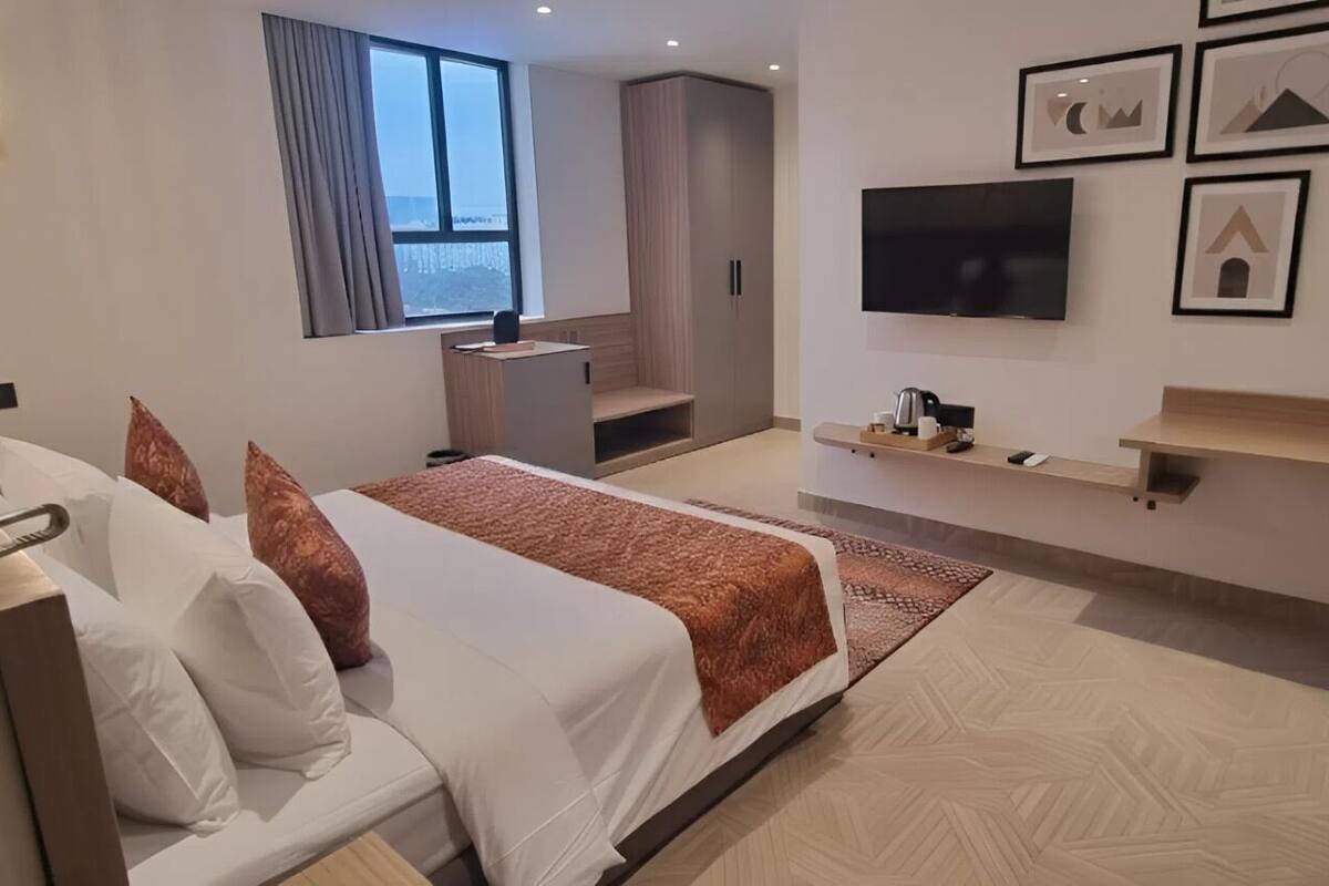 Habitación de hotel moderna con cama, escritorio, televisor y cuadros en la pared.