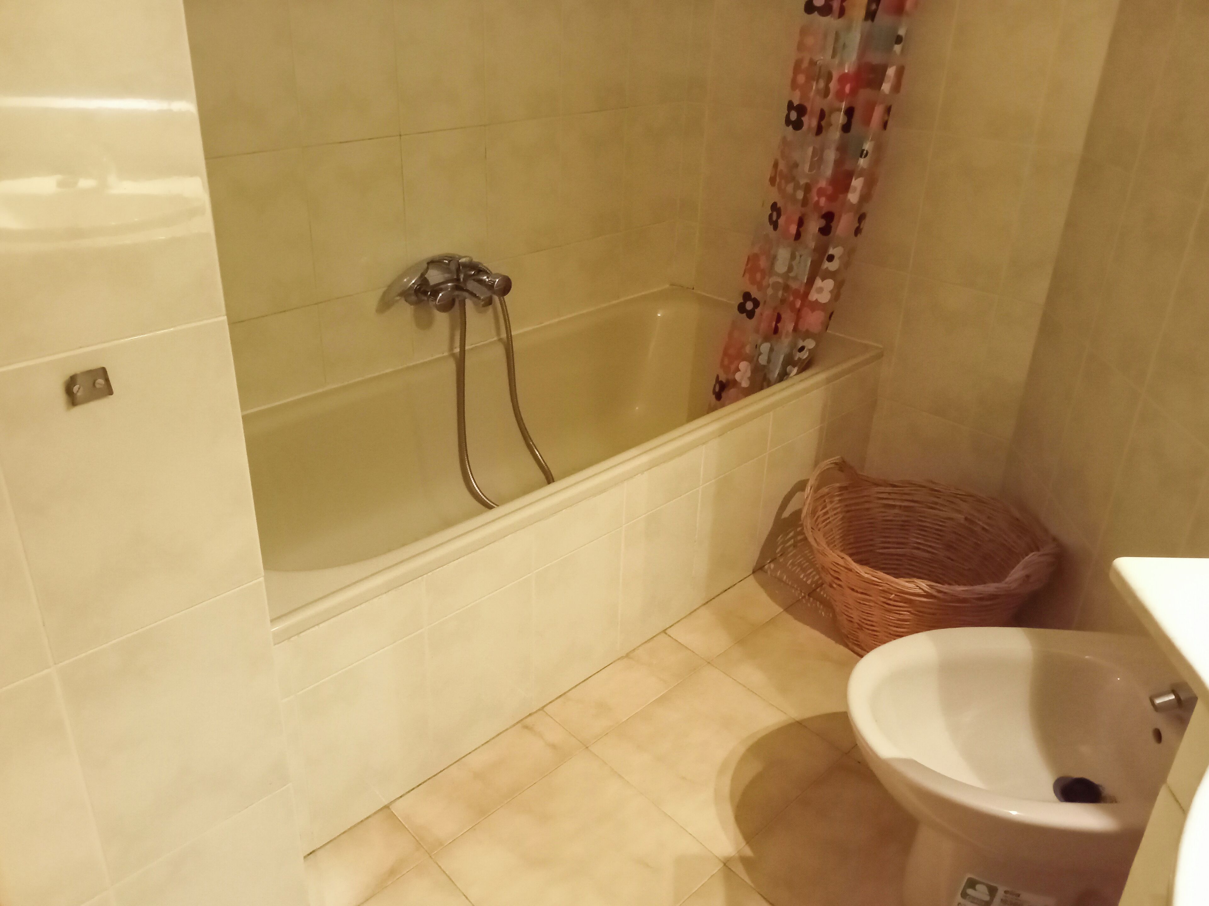 A bathroom with a bathtub, a toilet, and a wicker basket.