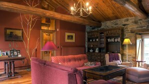 Una sala de estar acogedora con un sofá rojo, una mesa de centro de cristal y una estantería de piedra en la pared.