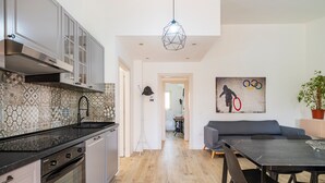 Une cuisine moderne dotée d’un four encastré, un coin repas avec une table et des chaises, et un salon avec un canapé.