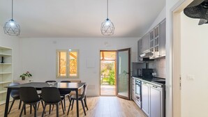 Une cuisine moderne avec un coin repas, un plancher en bois et des luminaires suspendus.