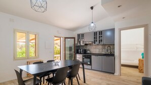 Une cuisine moderne avec des meubles de couleur grise, une table à manger avec des chaises et un luminaire suspendu.