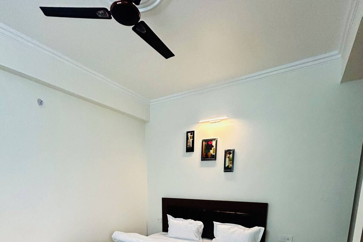 A bedroom with a bed, a ceiling fan, and wall-mounted lights.