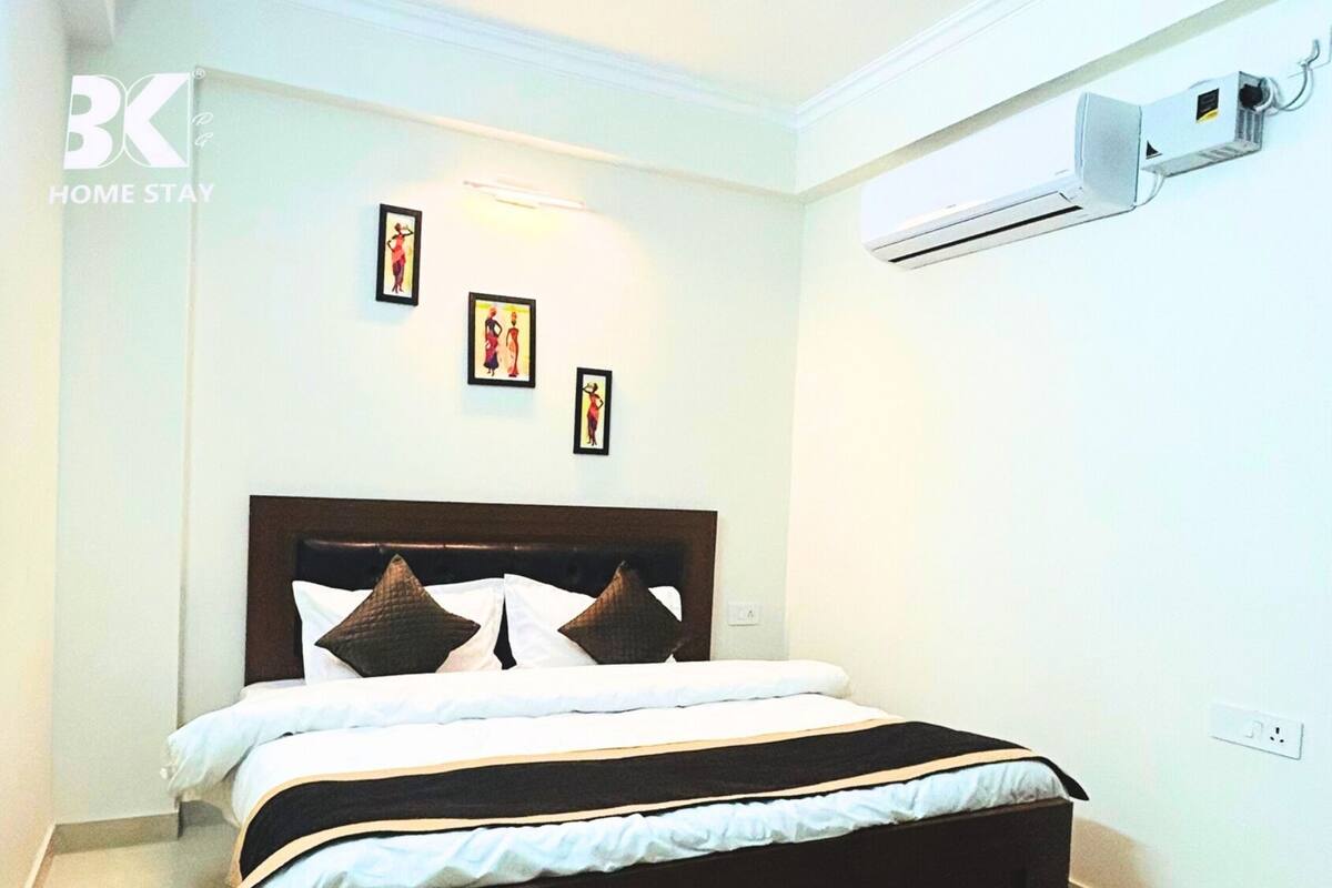 A bedroom with a bed, a headboard, and an air conditioning unit on the wall.