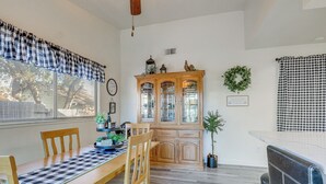 A dining area with a checkered tablecloth, wooden chairs, a wooden cabinet, and a potted plant. - Pet-friendly Yard! Home 3 Mi to Sky River Casino (Elk Grove)