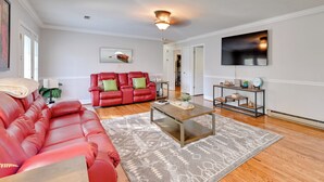 A spacious living room with a red leather sofa, a wooden coffee table, and a patterned rug. - Panther-ready Home 3 Mi to Hpu: Pet Friendly! (High Point)