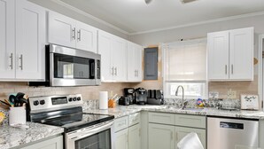 A modern kitchen with white cabinets, stainless steel appliances, and a granite countertop. - Panther-ready Home 3 Mi to Hpu: Pet Friendly! (High Point)
