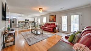 A spacious living room with a red leather sofa, a coffee table, and a flat-screen TV mounted on the wall. - Panther-ready Home 3 Mi to Hpu: Pet Friendly! (High Point)