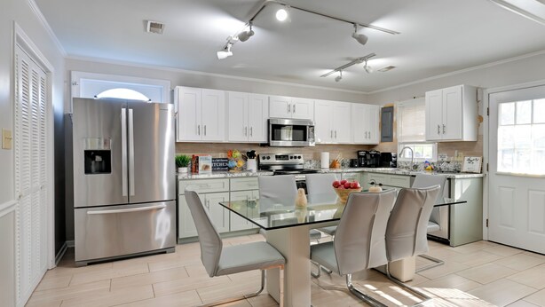 A modern kitchen with white cabinets, stainless steel appliances, and a glass dining table. - Panther-ready Home 3 Mi to Hpu: Pet Friendly! (High Point)