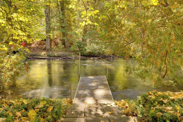 A wooden dock extending into a calm river surrounded by autumn foliage. - Cozy 'rivershire Retreat Cabin' Near Traverse City (Traverse City)