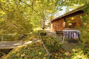 A wooden cabin with a table and chairs outside, a dock, and a pond. - Cozy 'rivershire Retreat Cabin' Near Traverse City (Traverse City)