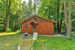 A cabin with a front porch, a small deck, and a grill area. - Cozy 'rivershire Retreat Cabin' Near Traverse City (Traverse City)