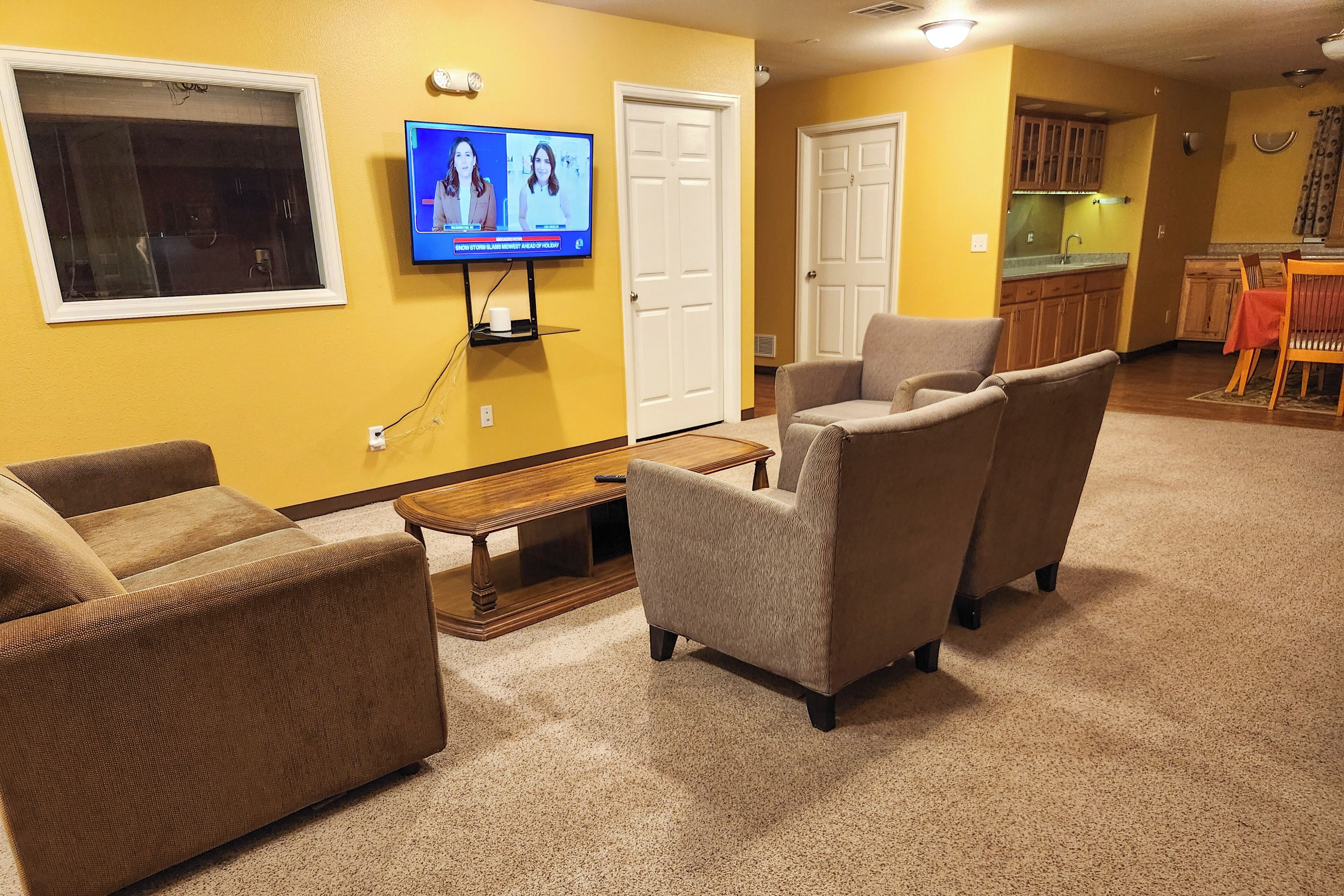 A living room with a television, two sofas, a coffee table, and a kitchen area in the background.