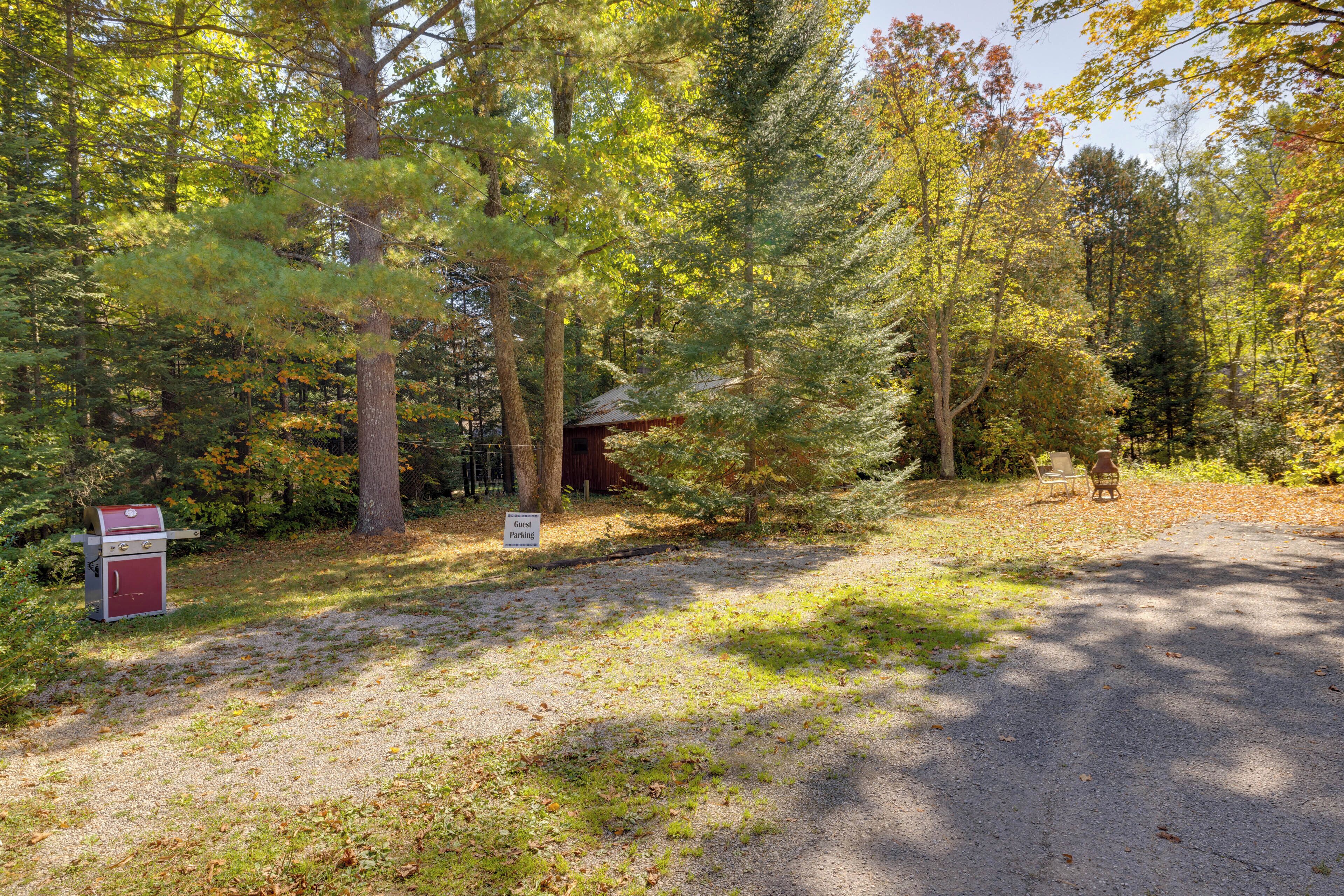 A gravel path leading to a cabin with a sign indicating guest parking.