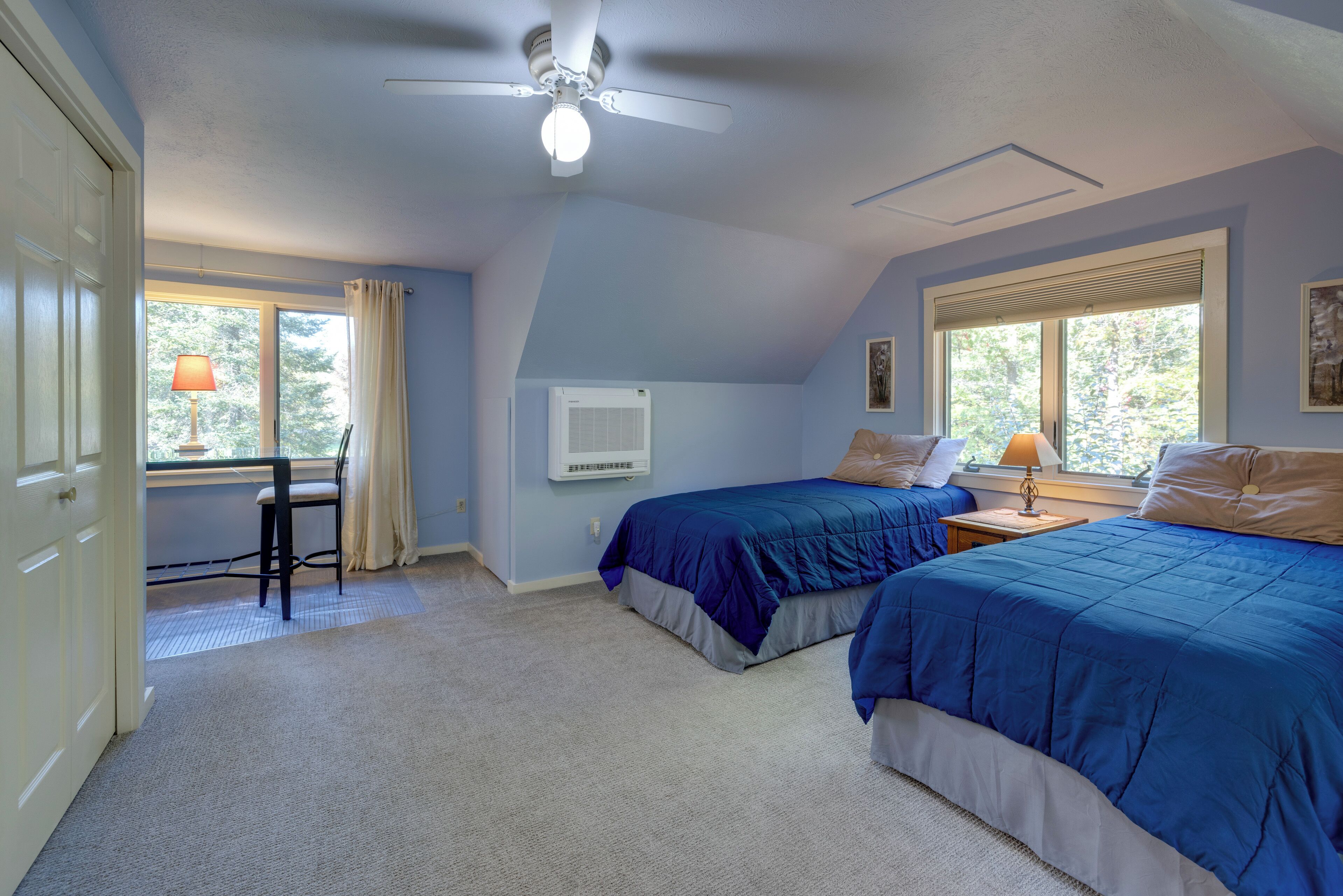 Une chambre avec deux lits, un ventilateur de plafond et un bureau avec une chaise.