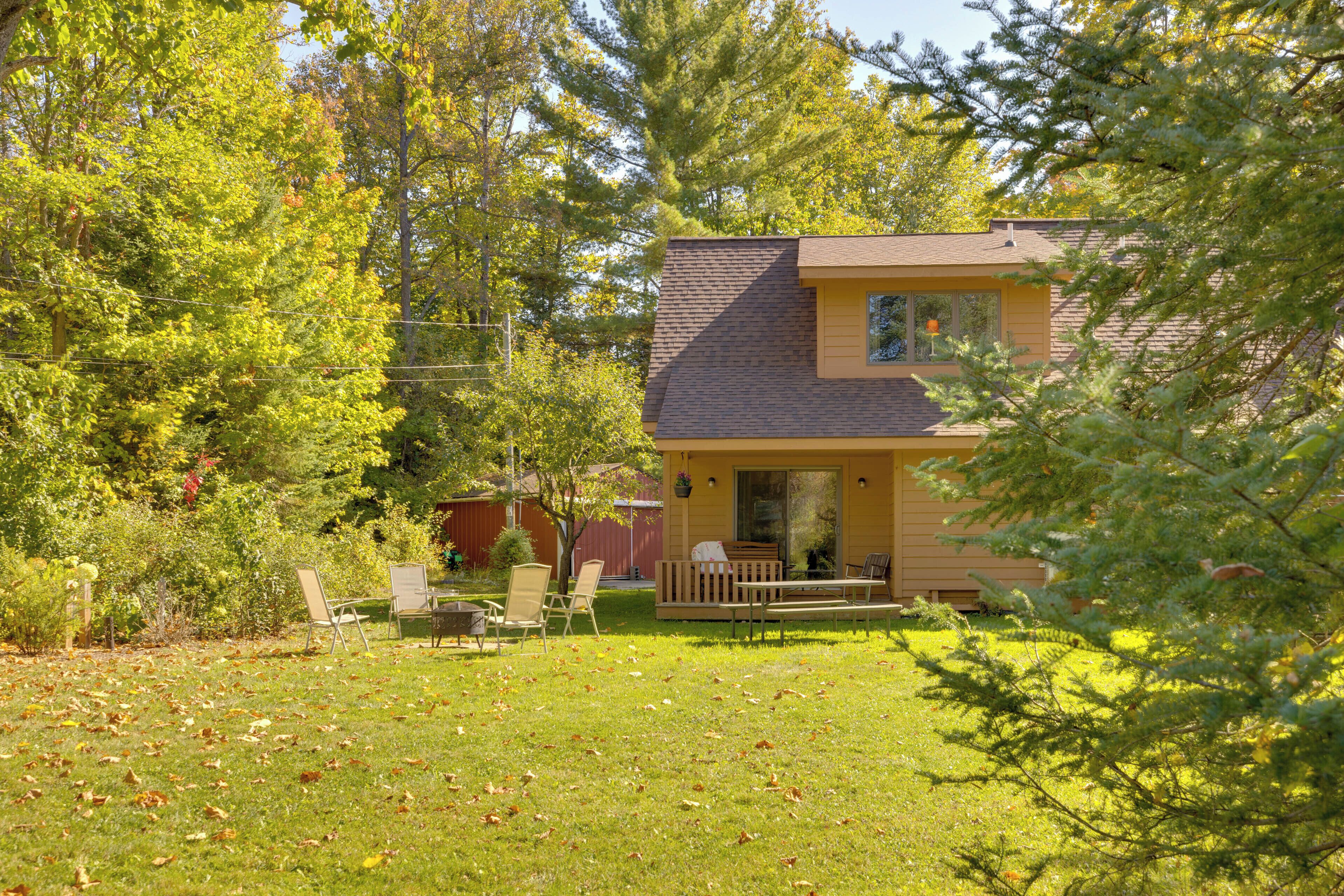 A house with a porch, a lawn, and a red barn in the background.