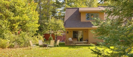 A house with a porch, a lawn, and a red barn in the background.