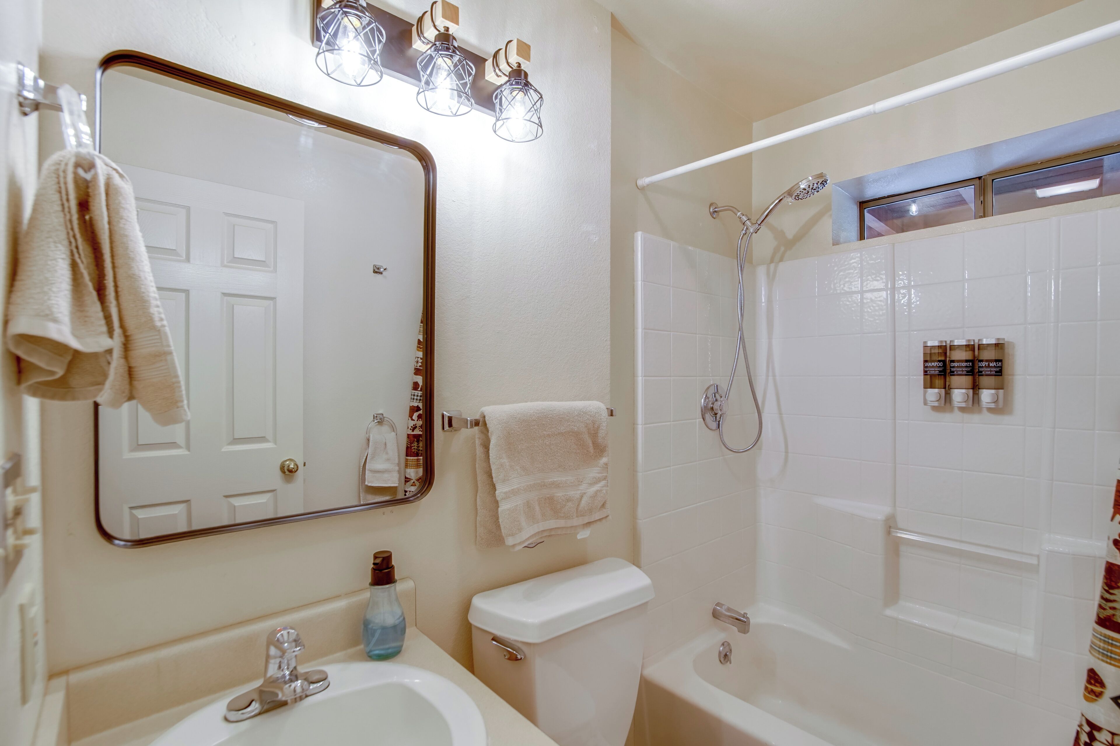 A bathroom with a sink, toilet, and bathtub. There are towels hanging on the wall and a mirror above the sink.