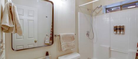 A bathroom with a sink, toilet, and bathtub. There are towels hanging on the wall and a mirror above the sink.