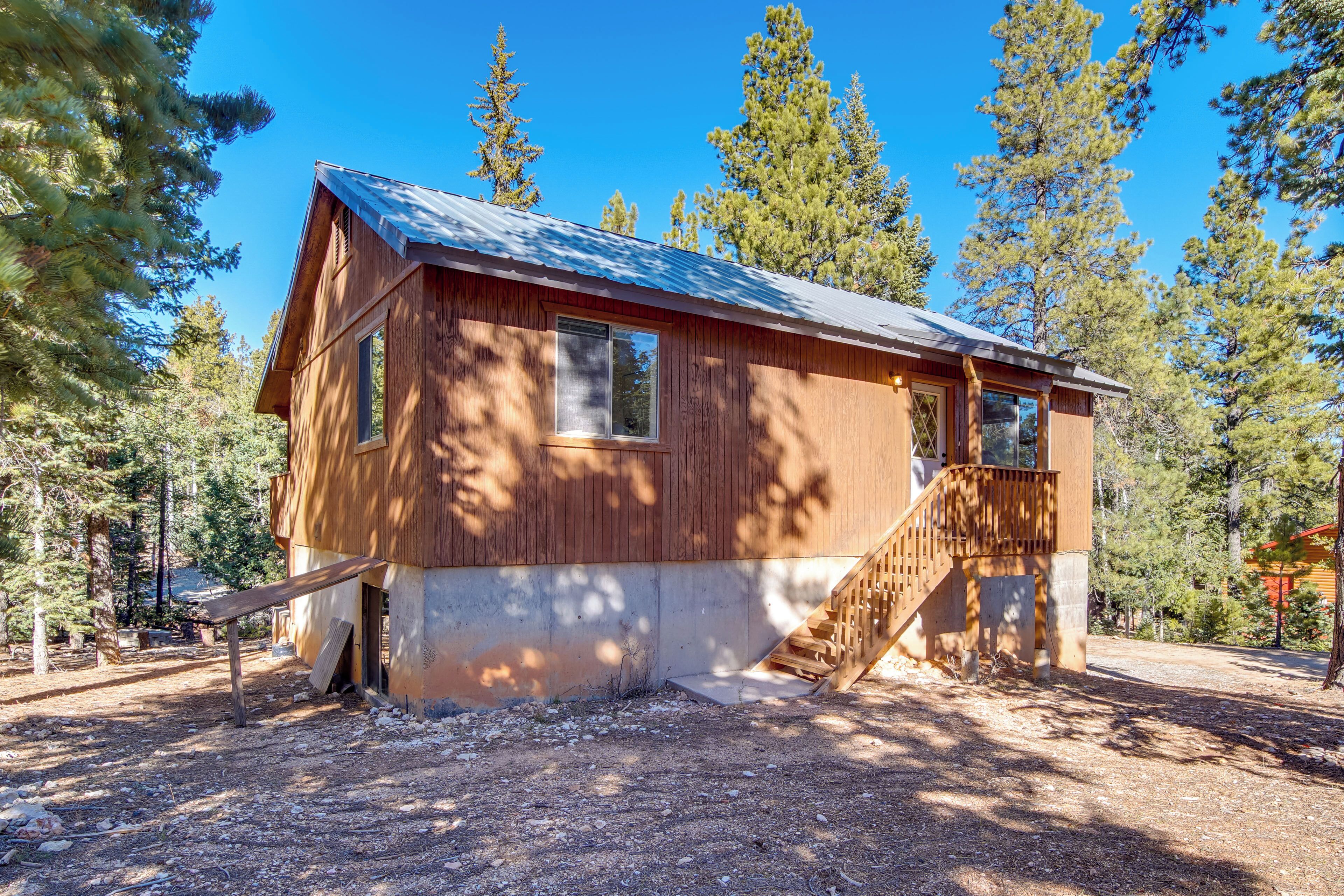 A wooden cabin with a metal roof, a wooden staircase, and a window.