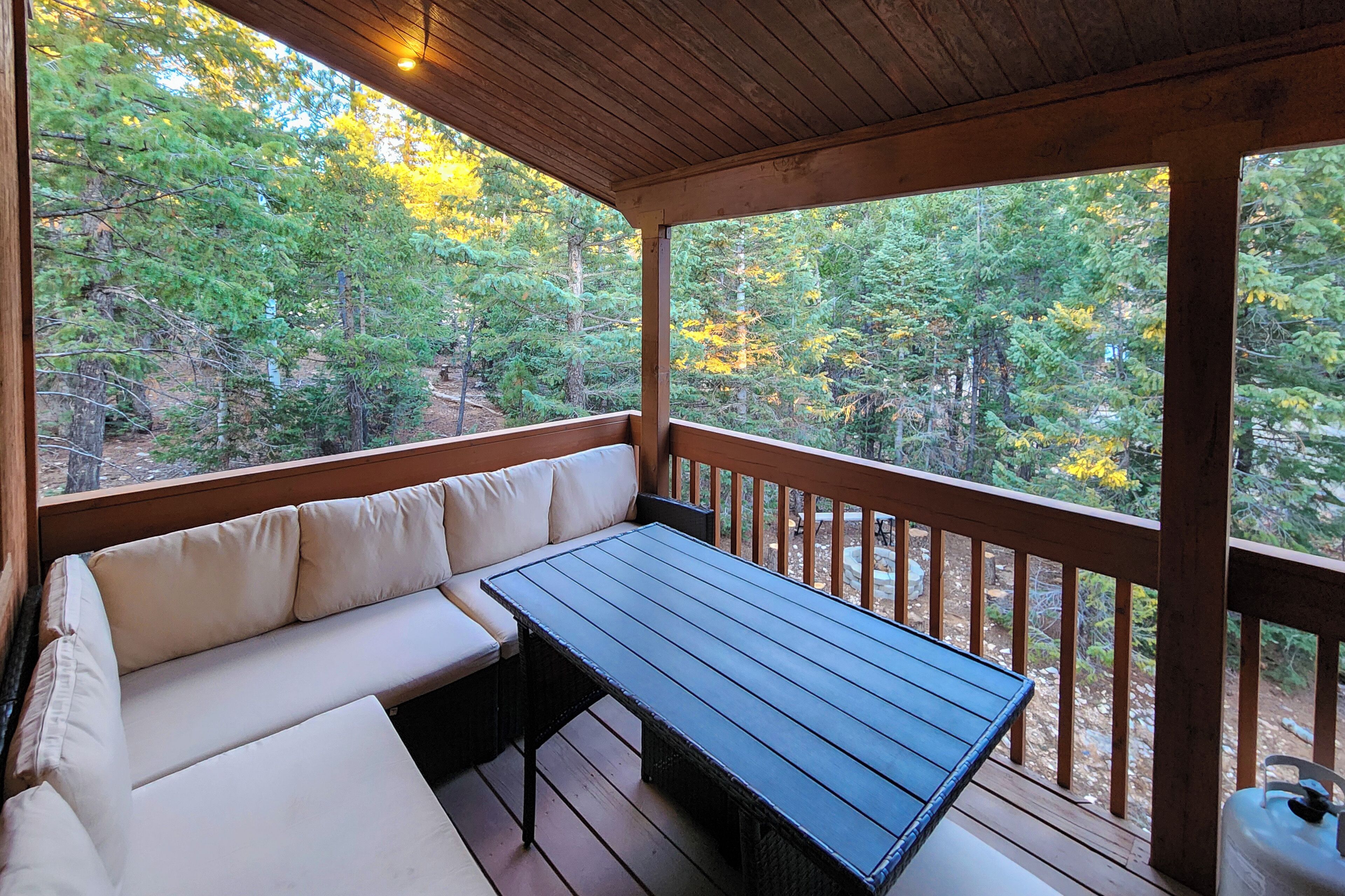 Un espace extérieur abrité, doté d’une terrasse en bois, d’un banc et d’une table.