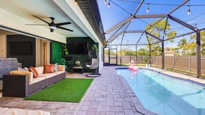 A covered outdoor area with a pool, a sofa, and a ceiling fan.