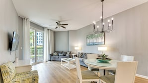 A modern living room with a sofa, a dining table with chairs, a ceiling fan, and a chandelier. - 1 Mi to Beach! Resort Retreat w/ Pool in Destin (Destin)