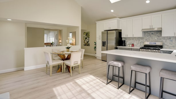 A modern kitchen with white cabinets, a large island, and bar stools.
