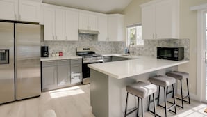 A modern kitchen with white cabinets, stainless steel appliances, and a large island with bar stools.