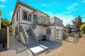 A two-story house with a front porch, a staircase, and a fenced backyard.