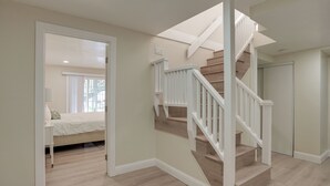 A spacious room with a large bed, a desk, and a staircase leading to another level.