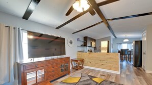 A modern living room with a large flat-screen TV, wooden cabinets, and a patterned rug. - Heart of Greensboro: Pet-friendly Gem 3 Mi to Dtwn (Greensboro)
