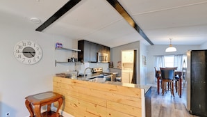 A modern kitchen with a central island, wooden cabinetry, and a built-in microwave. - Heart of Greensboro: Pet-friendly Gem 3 Mi to Dtwn (Greensboro)