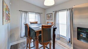 A dining area with a table set for four, wooden chairs, a chandelier, and a refrigerator. - Heart of Greensboro: Pet-friendly Gem 3 Mi to Dtwn (Greensboro)