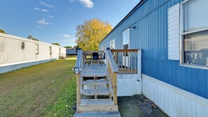 A wooden deck leading to a blue building with white trim, a grassy yard, and a tree with yellow leaves. - Heart of Greensboro: Pet-friendly Gem 3 Mi to Dtwn (Greensboro)