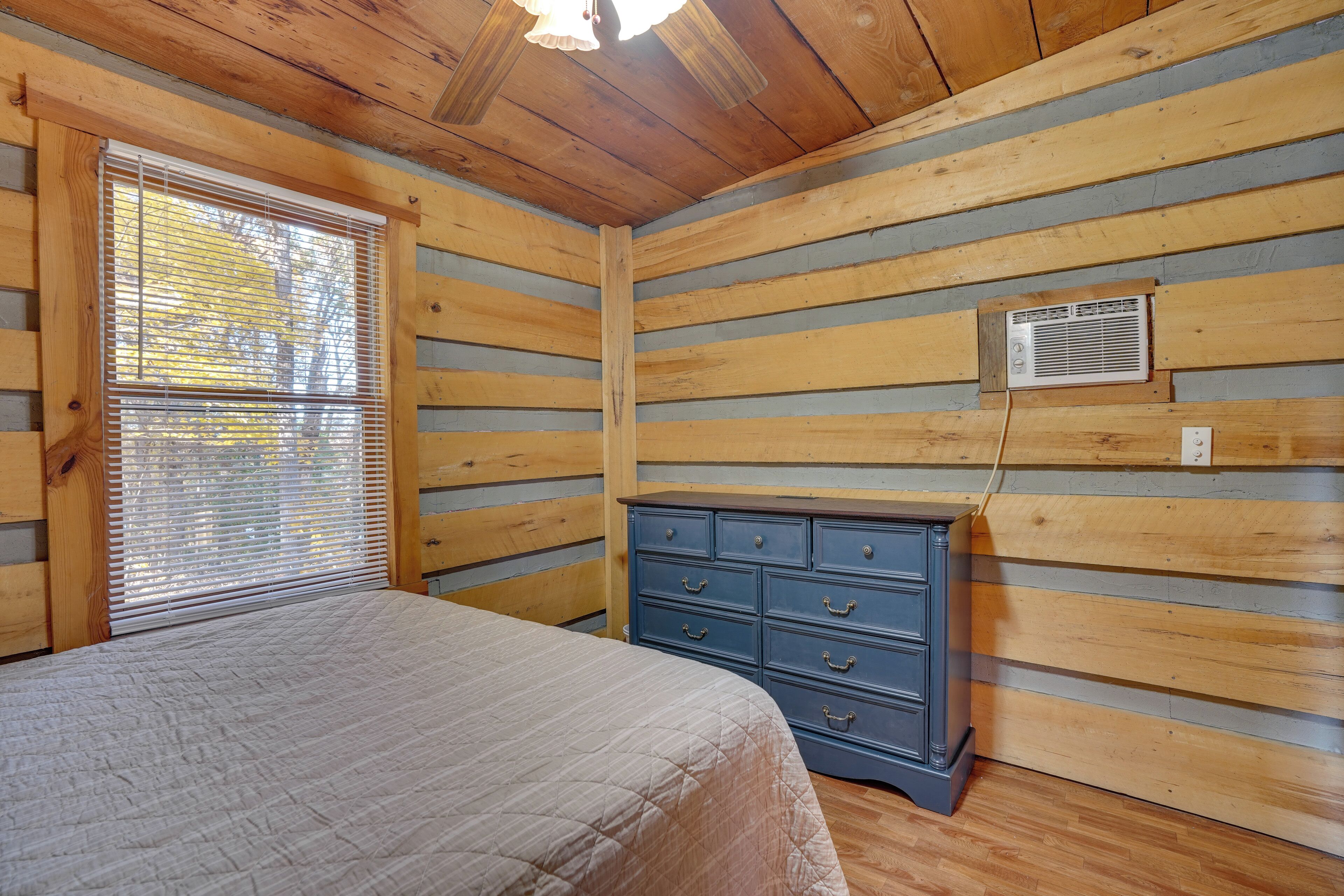 Un dormitorio con cama, cómoda, ventana con persianas y conducto de aire en la pared.