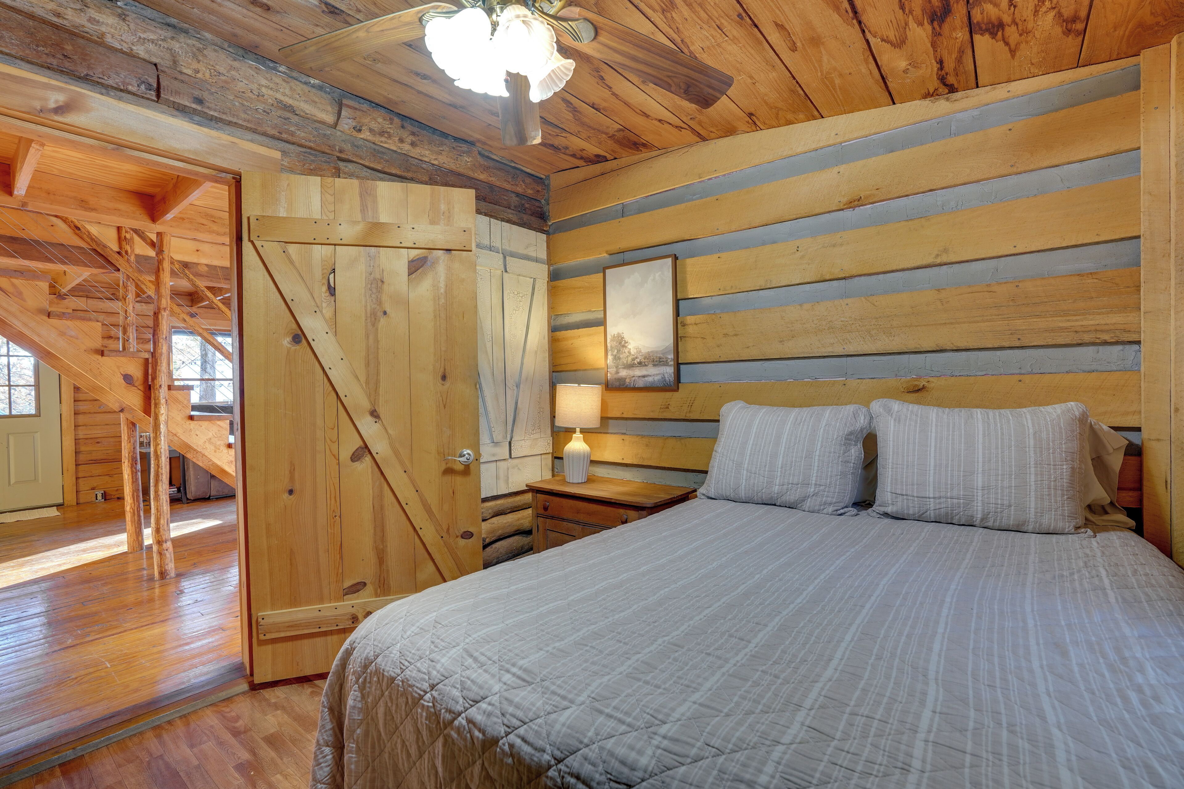 Une chambre à coucher en bois, avec un lit, une table de chevet et une porte donnant sur une mezzanine.