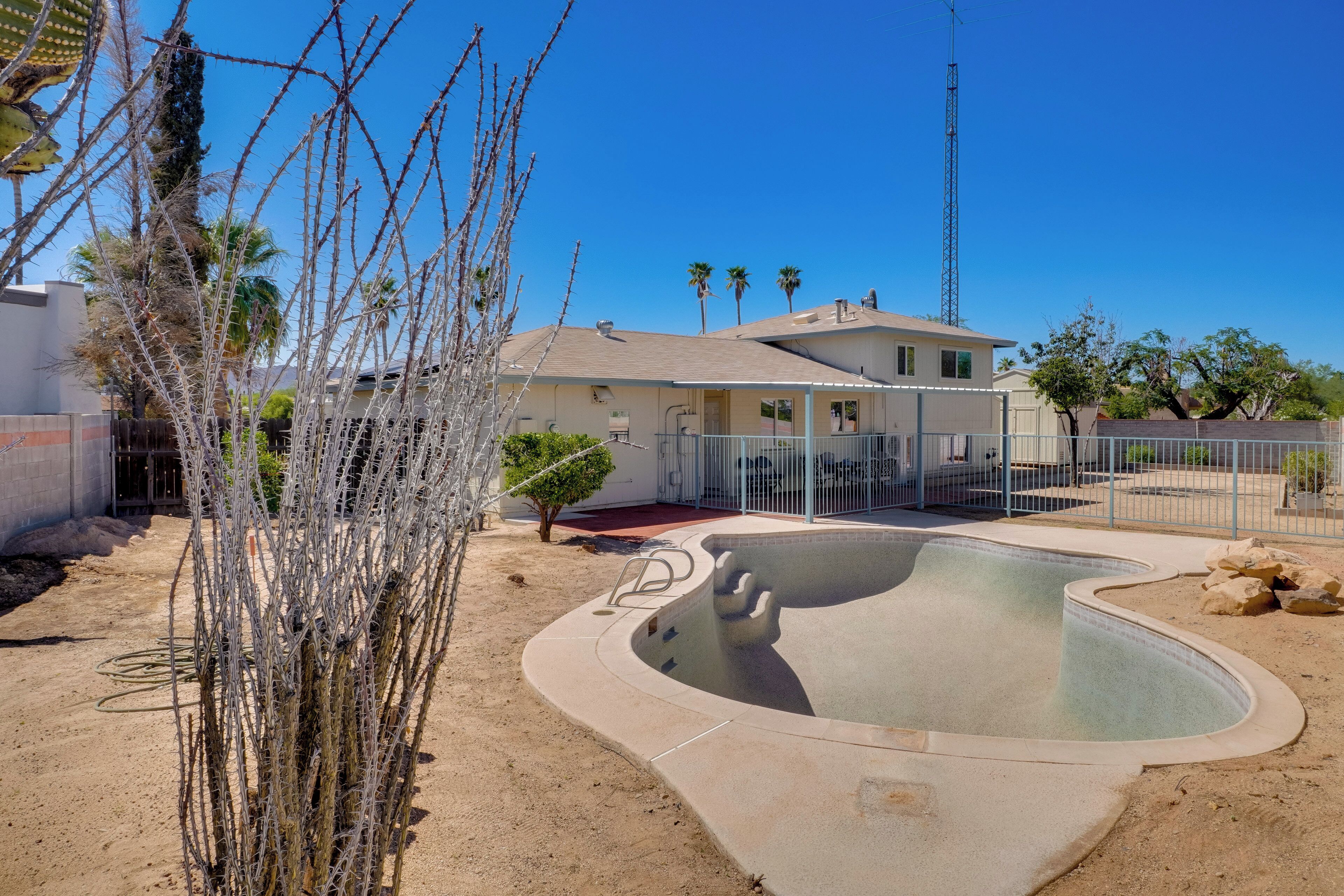 A residential area with a swimming pool, a house, and a tall communication tower in the background.