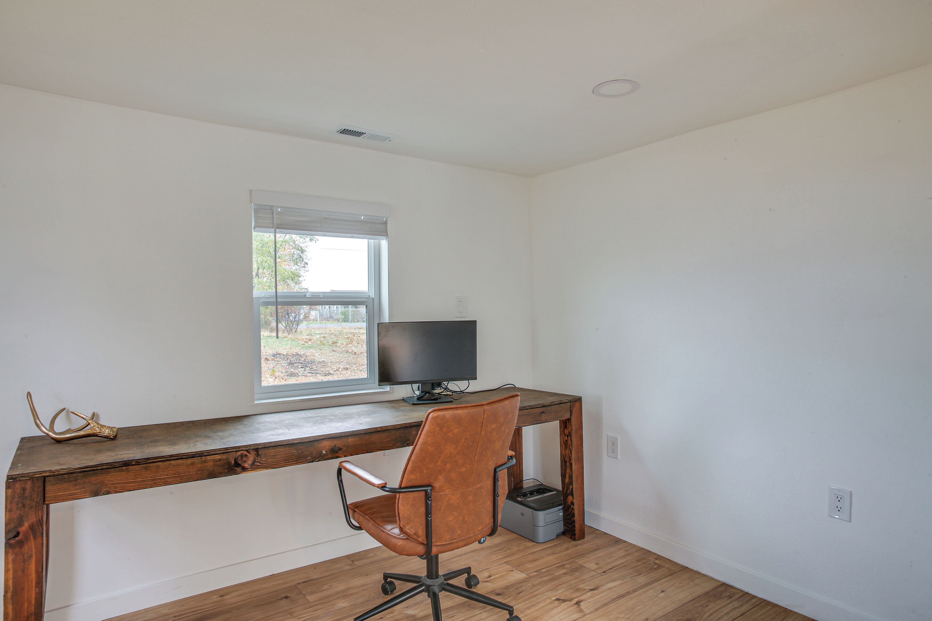 A room with a wooden desk, a computer, and a brown office chair.