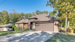 A two-story house with a garage, a brick exterior, and a well-maintained lawn. - Riders Retreat! Modern Home By Bella Vista Trails (Bella Vista)
