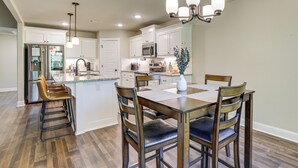 A modern kitchen with white cabinets, a central island, and bar stools. - Riders Retreat! Modern Home By Bella Vista Trails (Bella Vista)