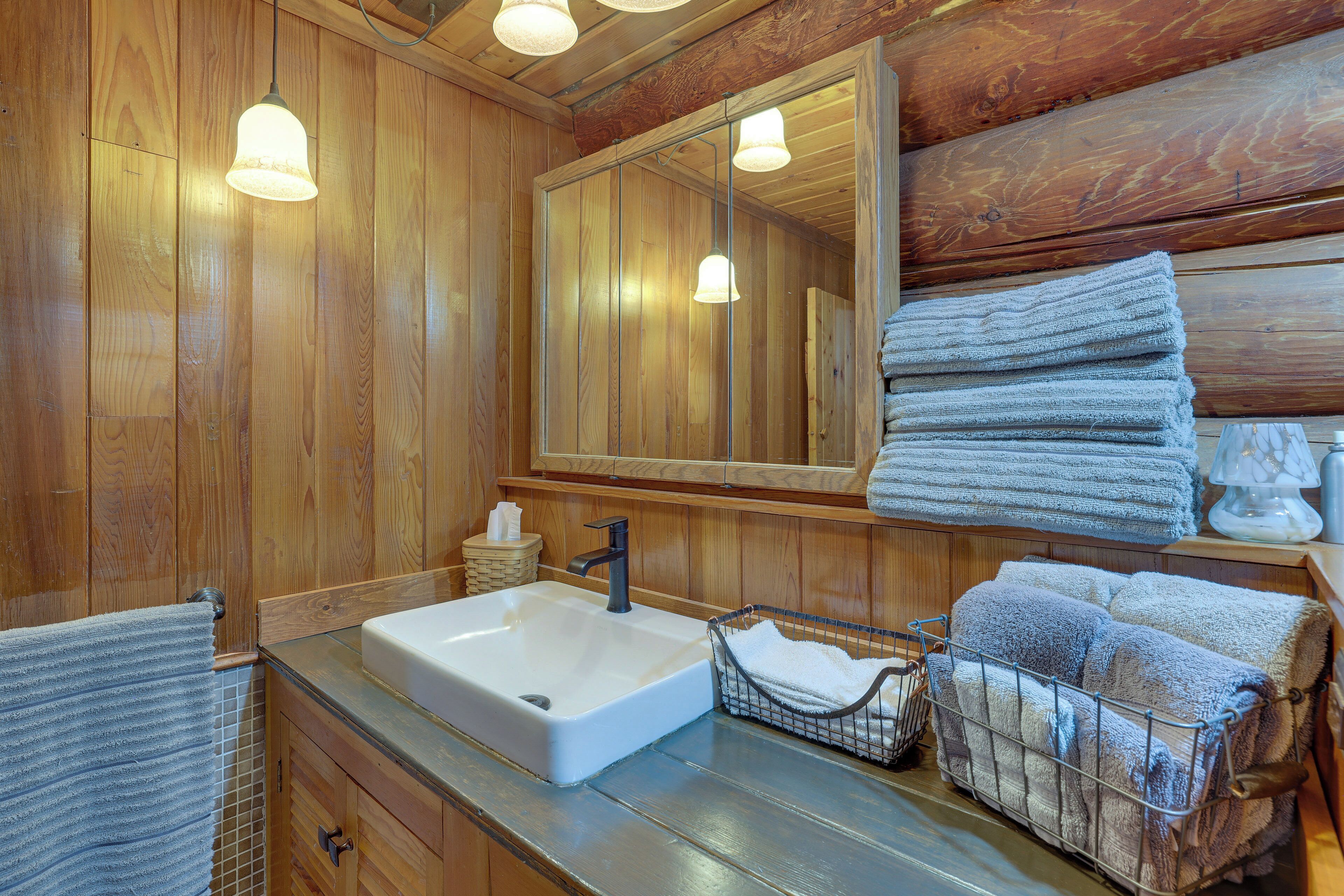 A wooden bathroom with a sink, mirror, and towels.